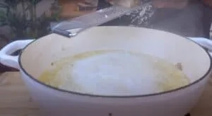 Grating cheese into a steaming pot of risotto on a wooden table, ready to enjoy.